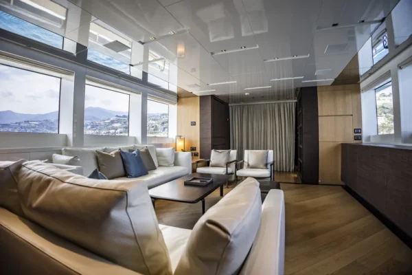 Luxurious main salon of the Sanlorenzo SL96 yacht featuring large windows and white sofas for charter in Porto Cervo, Sardinia.
