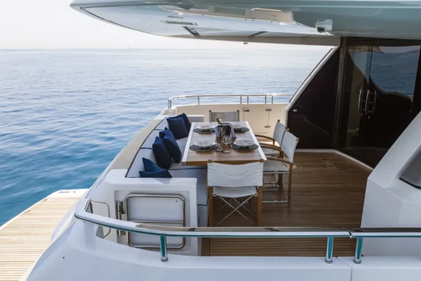 Spacious aft deck of the Sanlorenzo 96 featuring an alfresco dining table and comfortable sofa seating for charters in Costa Smeralda.
