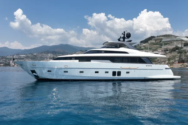 Profile view of the Sanlorenzo 96 yacht at anchor in a scenic bay in Costa Smeralda, Sardinia.