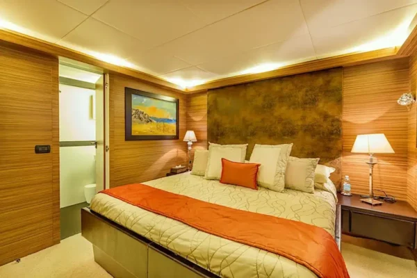 Spacious VIP double cabin on the Velvet 100 with a large bed, orange decor, and warm ambient lighting.