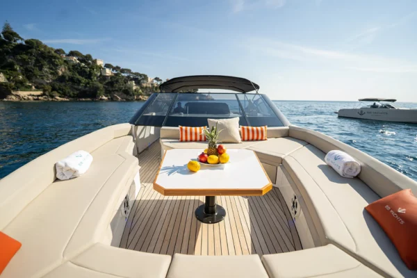 Perspective view from the bow seating area of the BB Yachts Panarea 44 looking toward the windscreen, featuring a white central table and beige cushions in Porto Cervo, Costa Smeralda, Sardinia.