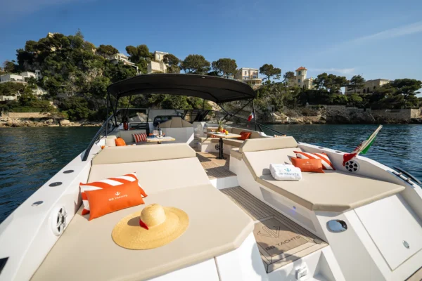 Wide stern sunbathing area of the BB Yachts Panarea 44 with beige cushions and orange accents overlooking the sea in Porto Cervo, Costa Smeralda.