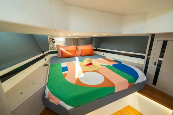 Master cabin of the BB Yachts Panarea 44 featuring a large bed with colorful linens and modern wooden finishes in Porto Cervo, Costa Smeralda, Sardinia.