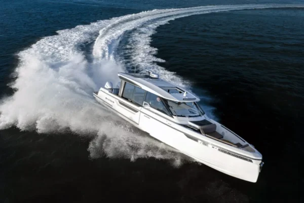 Aerial drone photograph of a Saxdor 400 GTO yacht speeding through the sea near Porto Cervo, Costa Smeralda, showing a prominent white wake and the vessel's high-performance hull.