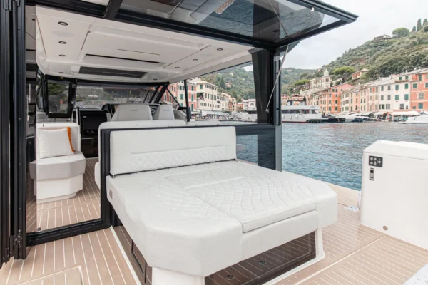 A view from the stern of the Saxdor 400 GTO looking forward, showcasing the large sunbathing bed and the seamless transition into the shaded social area, ideal for relaxing in the sun of Costa Smeralda, Sardinia.