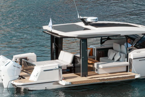 A high-angle shot of the Saxdor 400 GTO with its signature fold-down side terraces fully extended, creating a vast private beach club area for guests at anchor in the crystal-clear waters of Porto Cervo, Costa Smeralda, Sardinia.