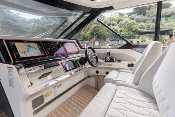 Modern helm station of the Saxdor 400 GTO equipped with dual digital Garmin displays and white diamond-stitched pilot seats for precise navigation in the Costa Smeralda.