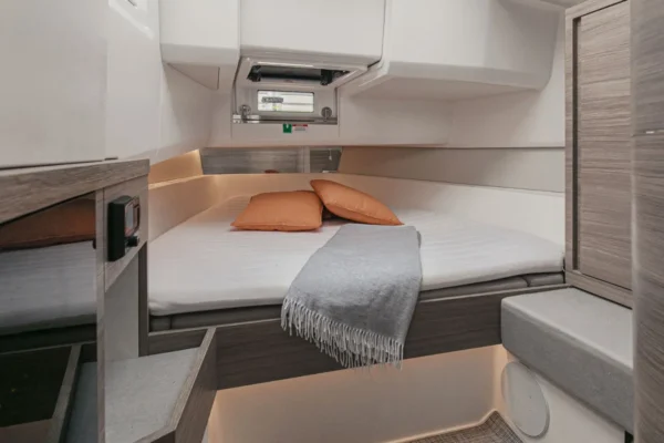Interior of the forward master cabin on the Saxdor 400 GTO featuring a double bed with neutral tones and natural light, offering luxury accommodation for Sardinia yacht rentals.