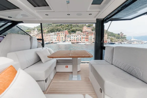 Interior view of the Saxdor 400 GTO yacht deck lounge featuring light gray modular seating, a teak table, and high-end finishes for luxury charters in Porto Cervo, Costa Smeralda, Sardinia.