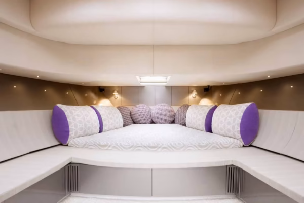 Interni eleganti e moderni della cabina sottocoperta dello yacht Continental 50, caratterizzati da un ampio letto matrimoniale con cuscini decorativi bianchi e viola e finiture chiare.