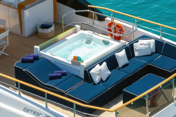 High-angle close-up view of the Amer F100 superyacht flybridge jacuzzi surrounded by navy blue lounge seating and plush white cushions.