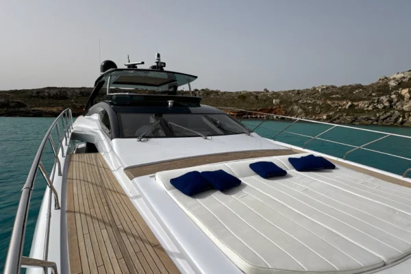 Foredeck of the Amer F100 superyacht showing large white sunbathing pads with navy blue cushions on teak decking facing the windshield and upper hardtop.