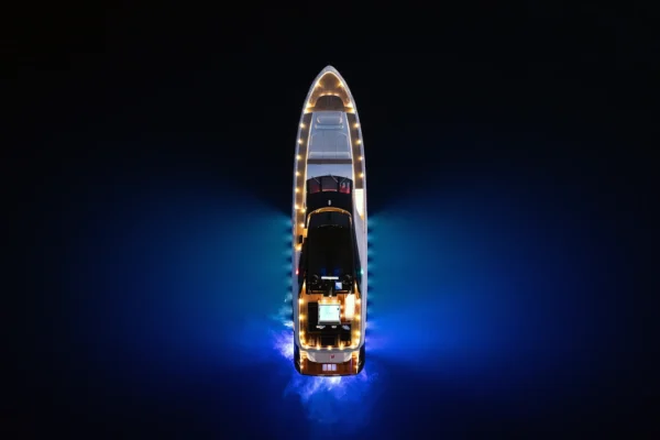 Direct overhead aerial view at night showing the Amer F100 superyacht illuminated with blue underwater LED lighting and deck illumination.