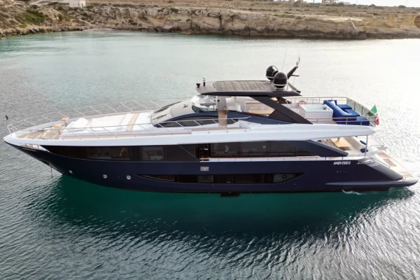 A close-up side profile view of the Amer F100 superyacht's central section, emphasizing the massive floor-to-ceiling glass windows of the main salon.