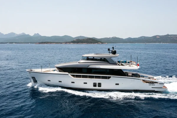 Port side profile of the Sanlorenzo SX88 luxury yacht navigating through blue water at speed, showcasing its sleek exterior design, open flybridge, and dark glass windows.