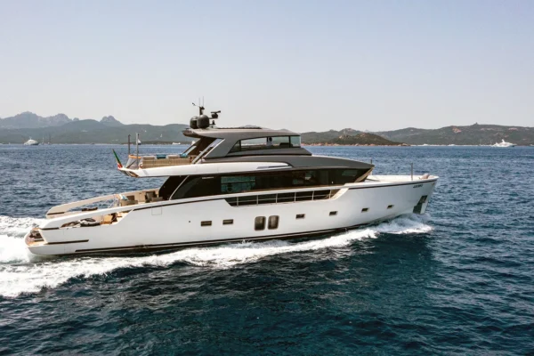 Starboard side profile of the Sanlorenzo SX88 motor yacht actively cruising through blue water, displaying its modern hull design, dark tinted windows, and open flybridge deck.