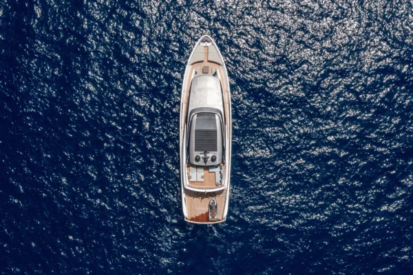 Direct overhead aerial view of the Sanlorenzo SX88 floating on deep blue water, displaying the full deck layout including the bow lounge, flybridge roof, aft deck, and swim platform with a jet ski.