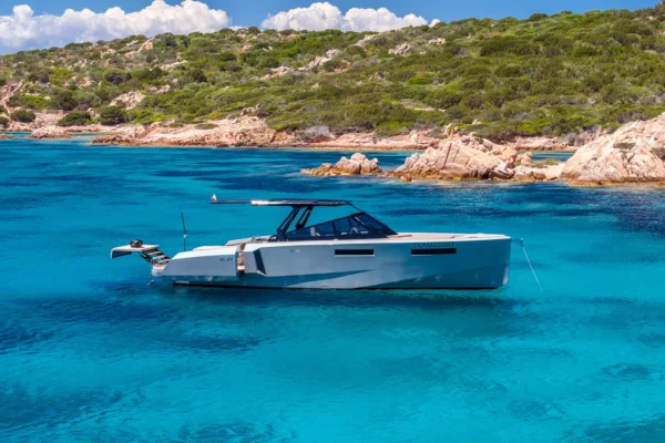 Side view of the EVO 43 WA motor yacht anchored in clear blue waters. The vessel features a sleek grey hull, a black hardtop, and an extended hydraulic stern platform with steps leading directly into the sea.